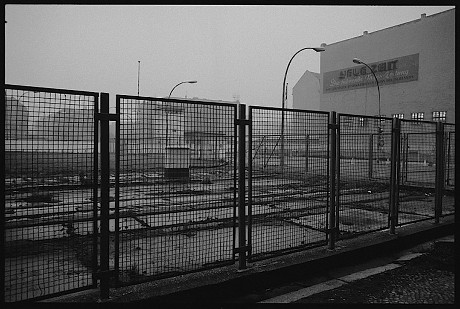 Photographie noir et blanc d'un grillage dans une zone industrielle