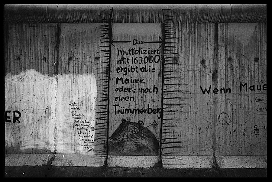 Photographie noir et blanc de différents messages taggés sur le mur de Berlin