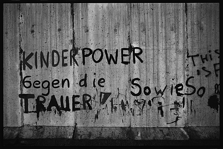 Photographie noir et blanc de différents tags sur le mur de Berlinois comprennant différents message en allemand