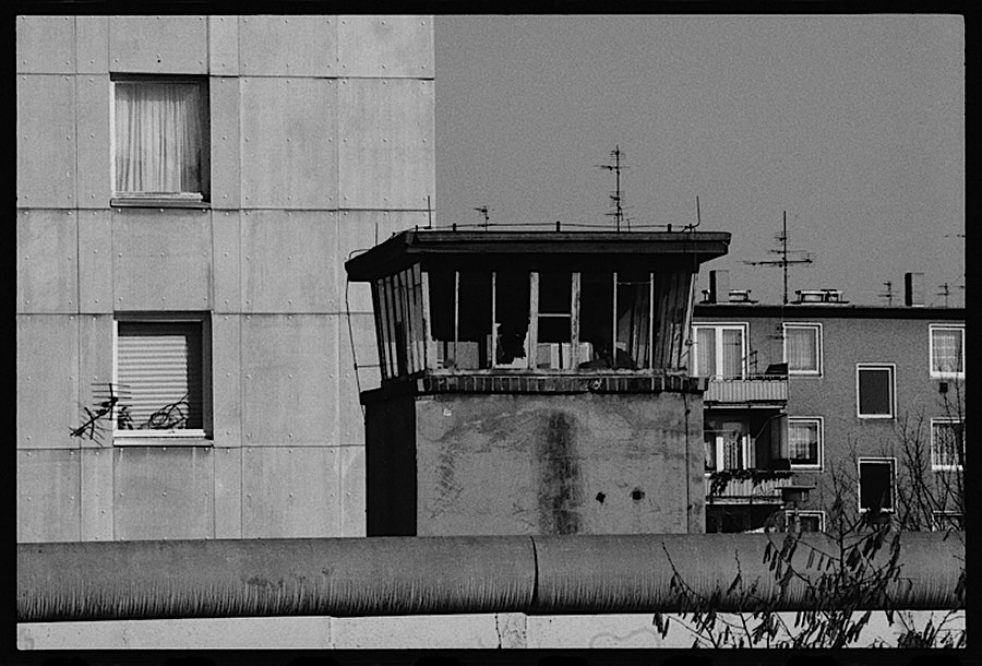 Photographie noir et blanc et rapprochée du haut d'une tour de garde,avec des immeubles en arriére plan