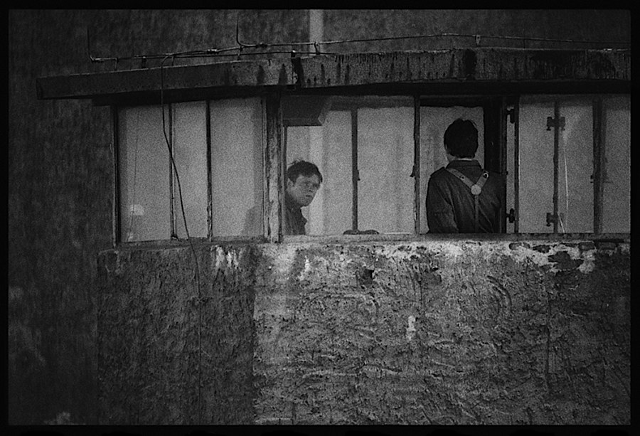 Photographie noir et blanc de deux gardes en haut d'une tour de garde du mur séparant les deux Berlin