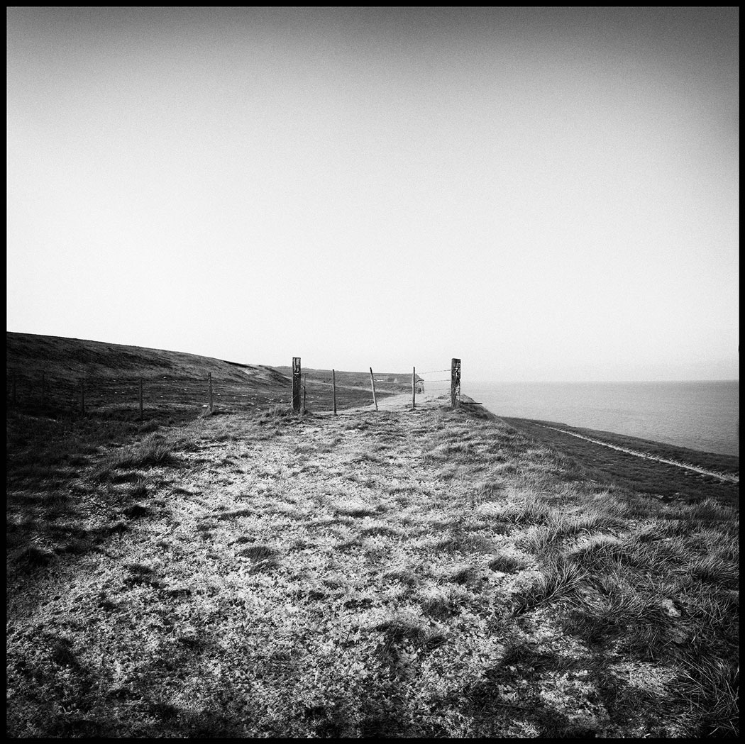 Photographie numérique d'une barrière menant à un champ en bord de falaise en Picardie