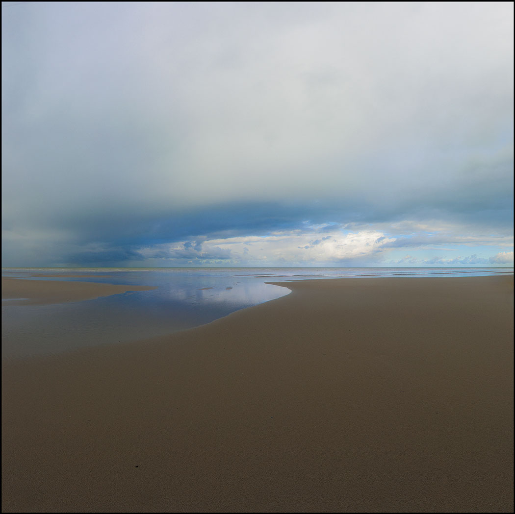 Photographie numérique d'une plage au sable lisse dirigé vers la mer
