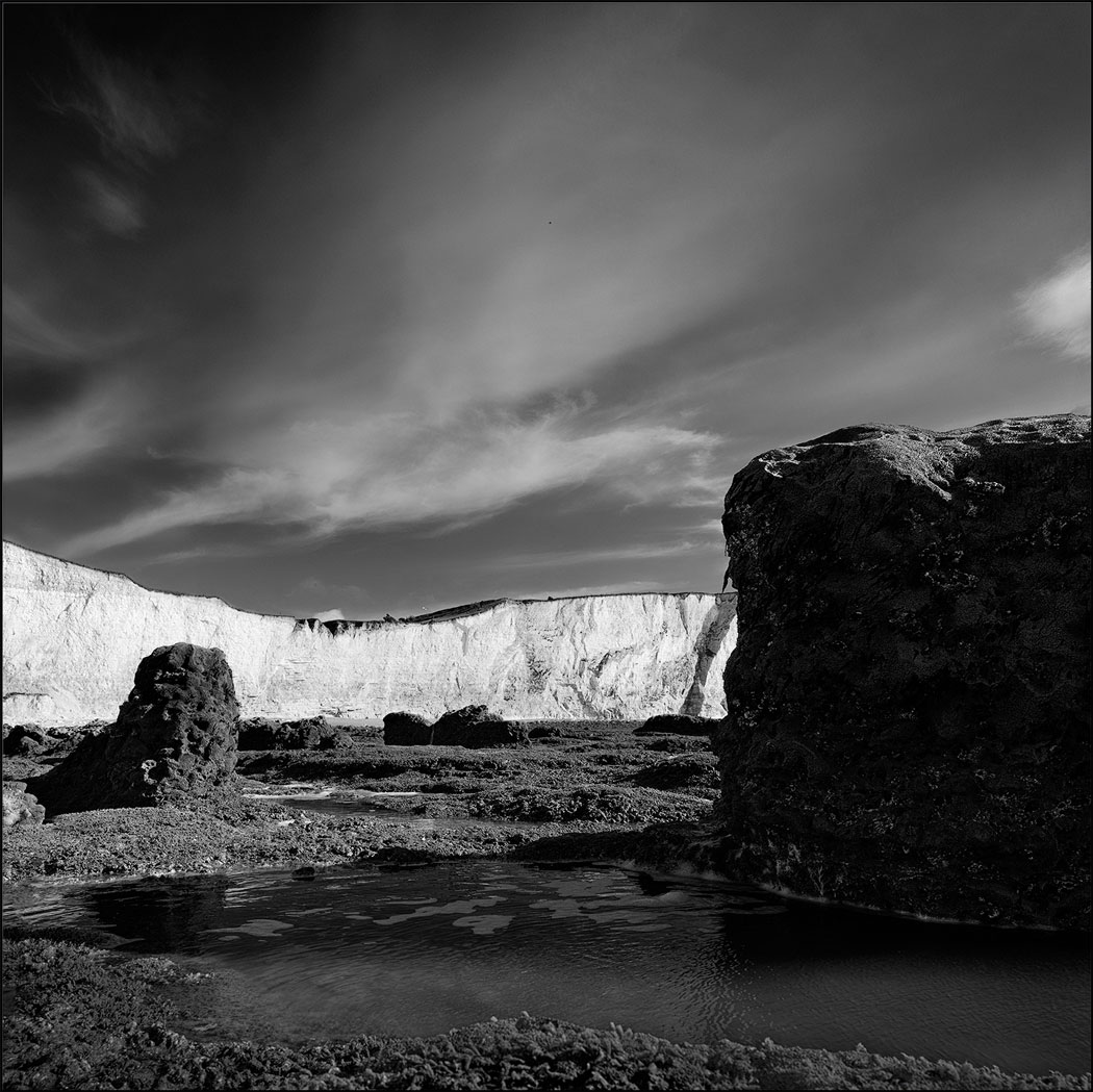 Photographie numérique en noir et blanc avec un rocher en premier plan et la falaise en arrière plan